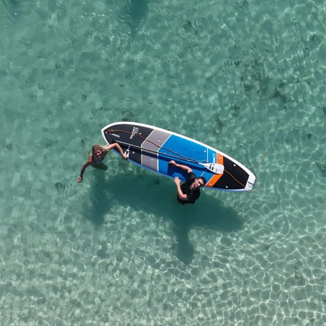 Stand up paddle boarding over clear shallow water